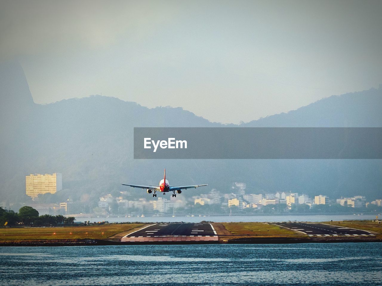 Airplane landing on runway by mountains against sky