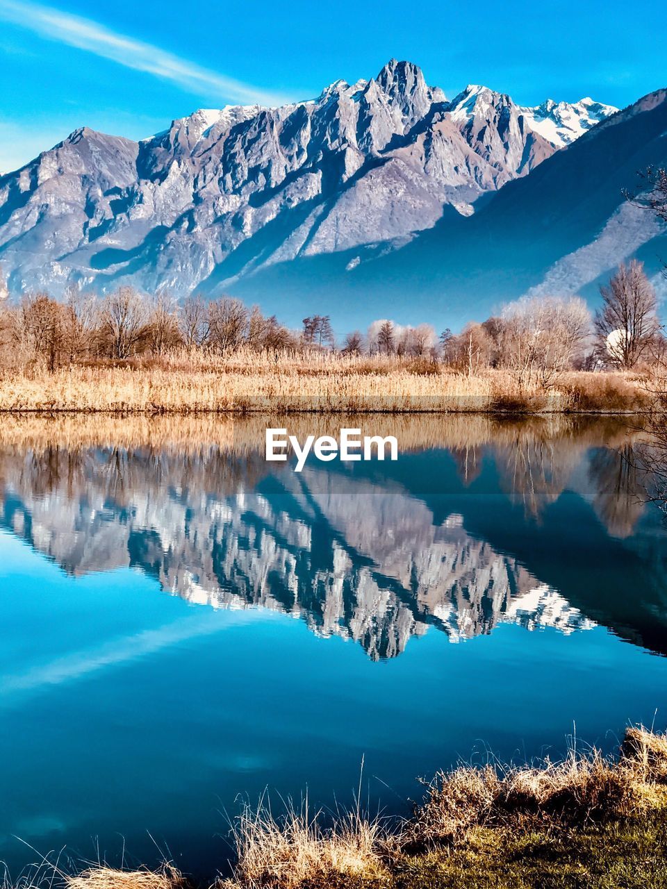 Scenic view of lake by snowcapped mountains against sky