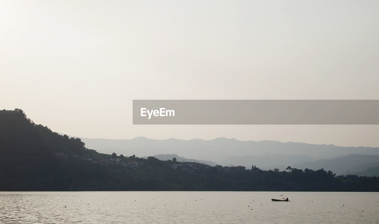 Scenic view of seascape by mountains against clear sky