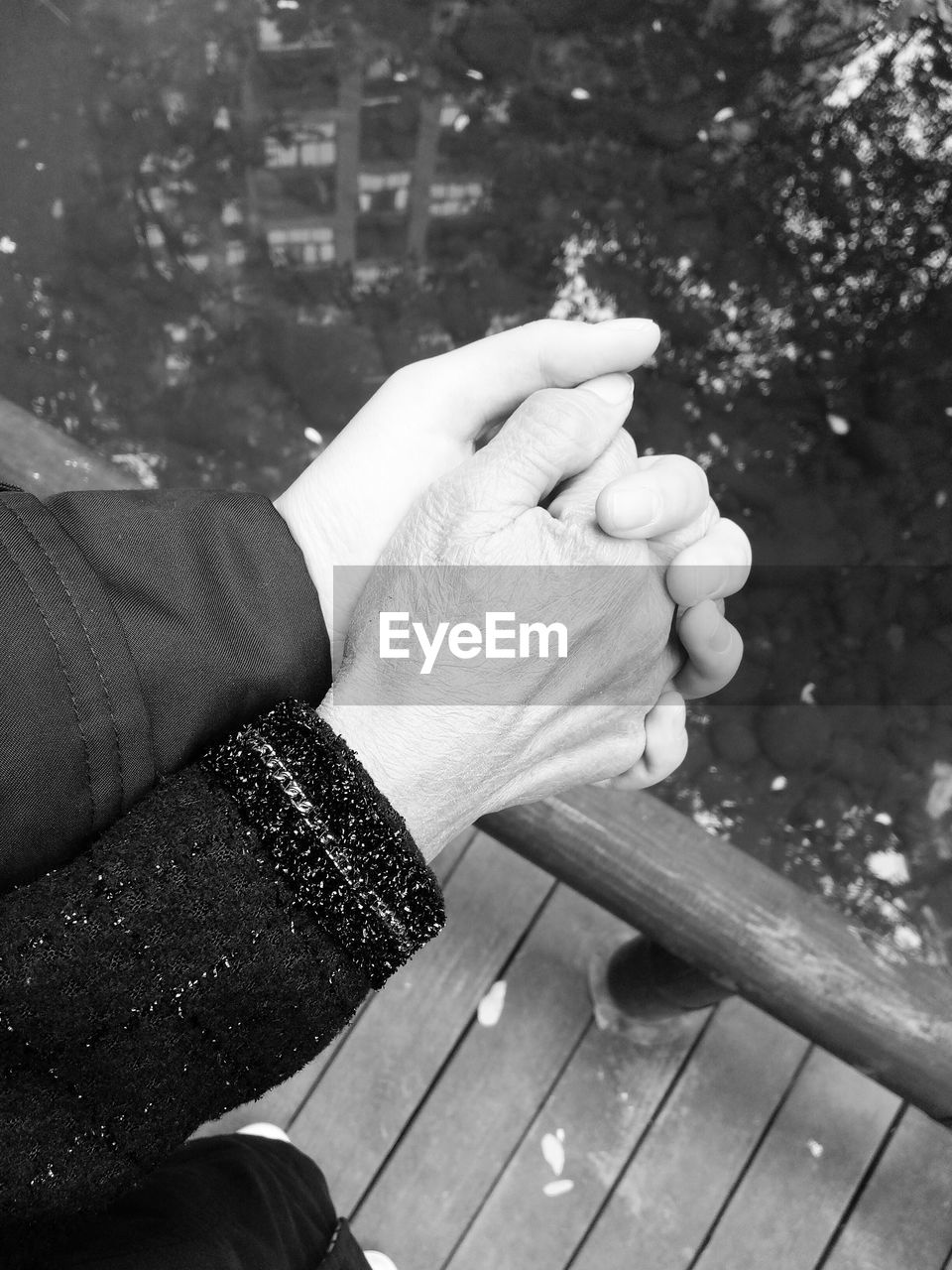 Cropped image of couple holding hands on pier by sea