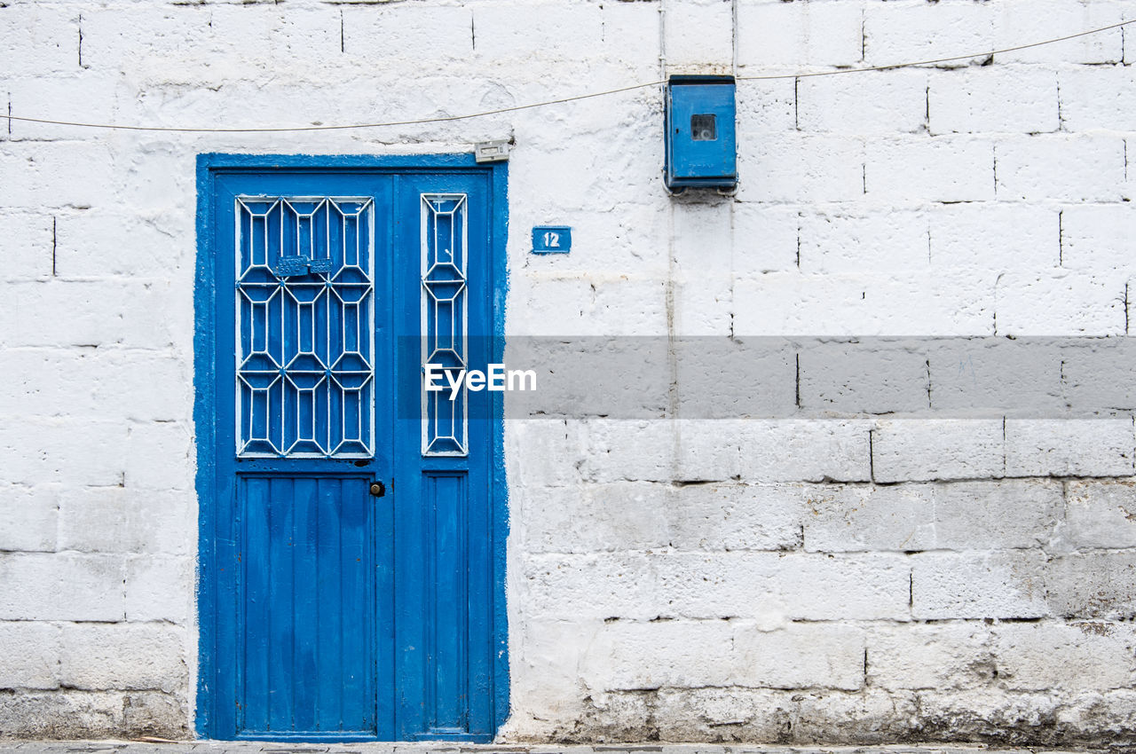 Closed blue door against white concrete wall house