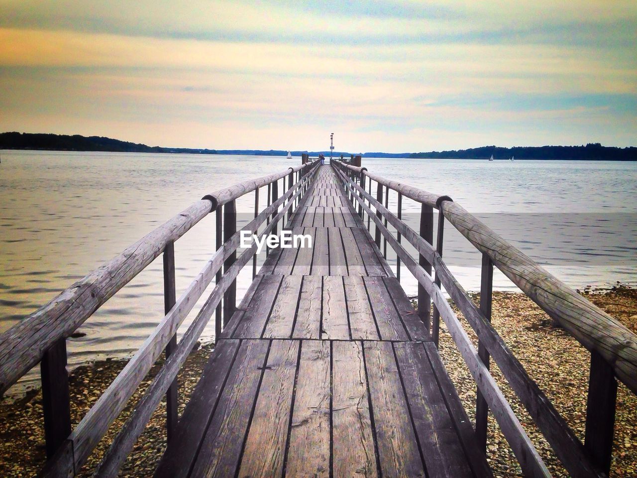 Pier over lake against sky at sunset