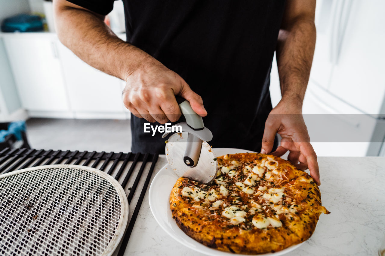 Close up shot of man slicing pizza