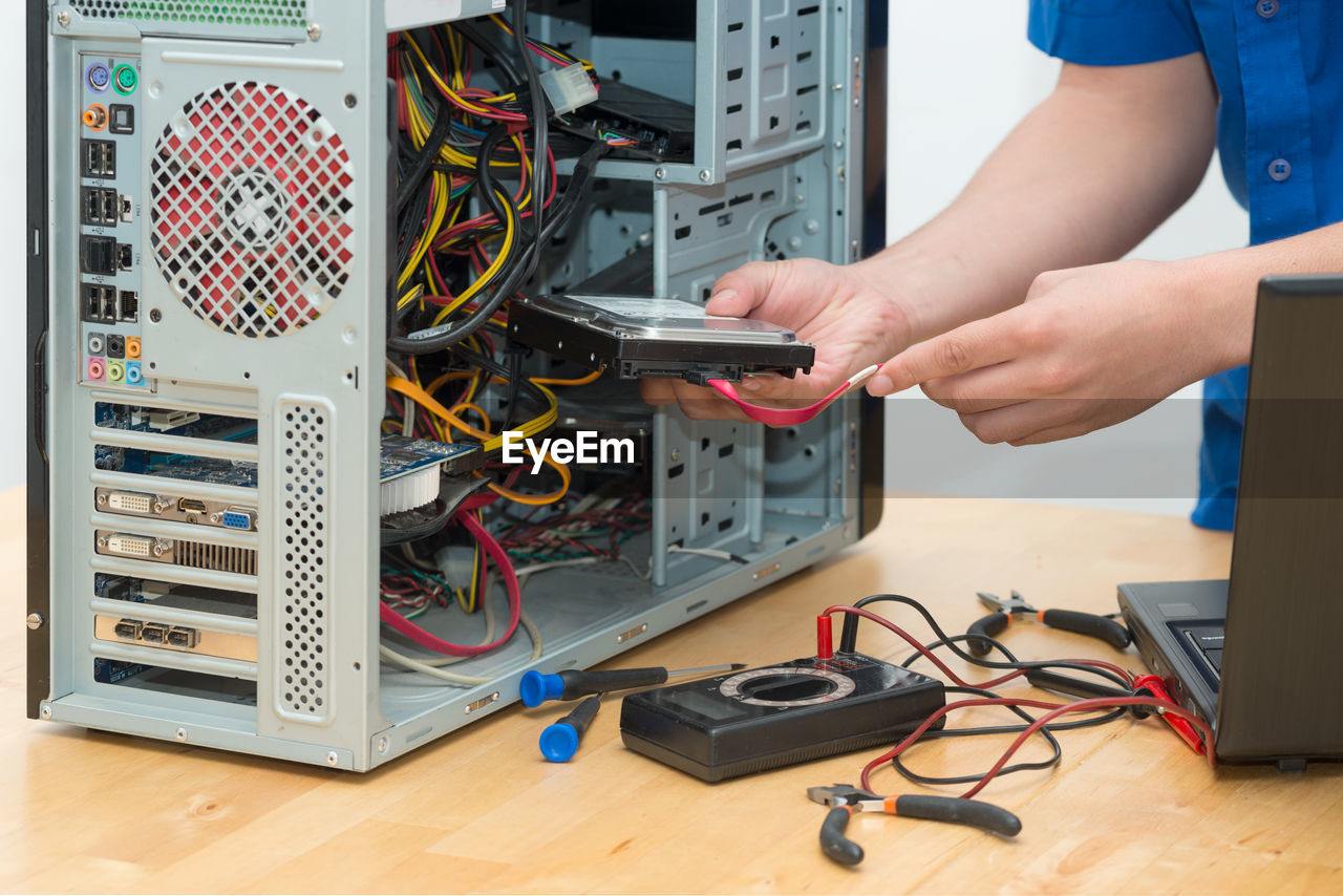 Midsection of man repairing computer on desk