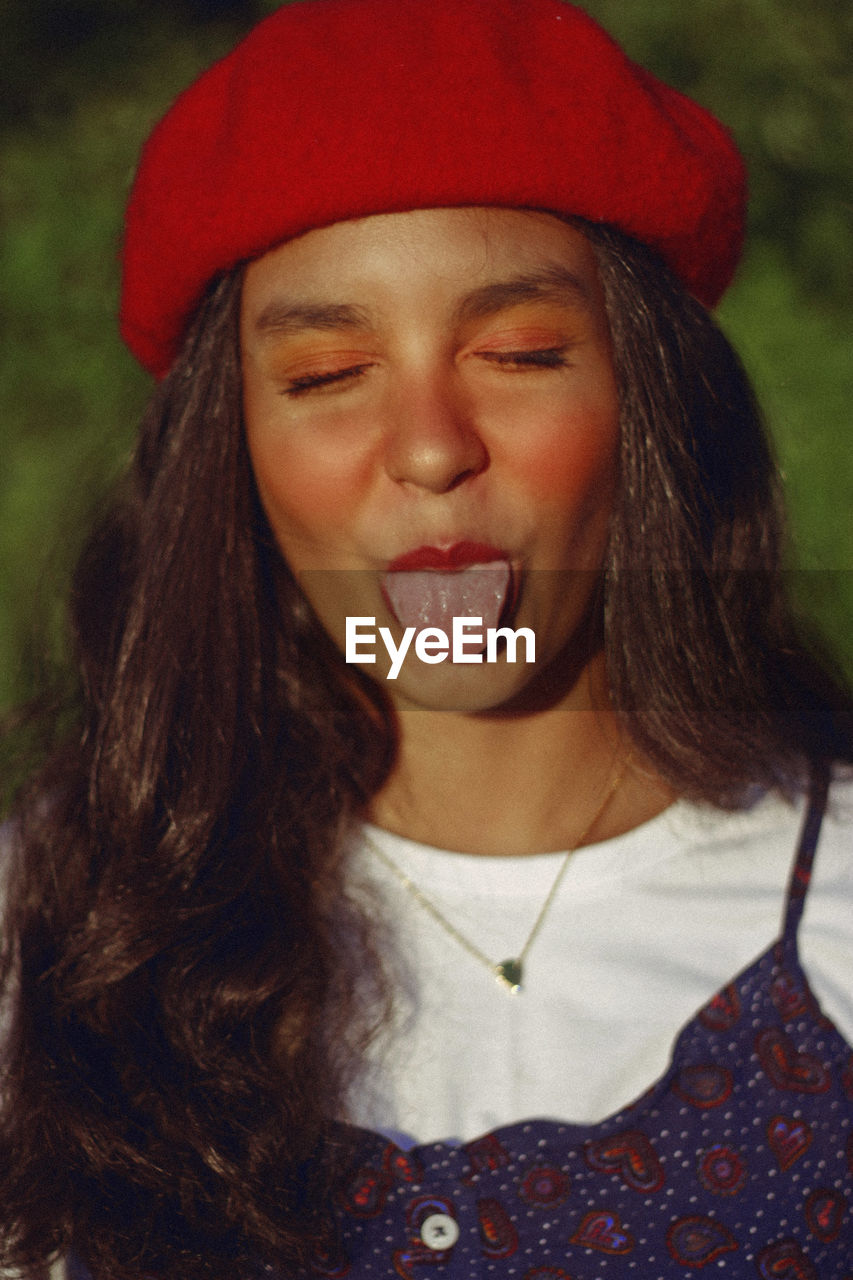 Close-up of young woman sticking out tongue at night