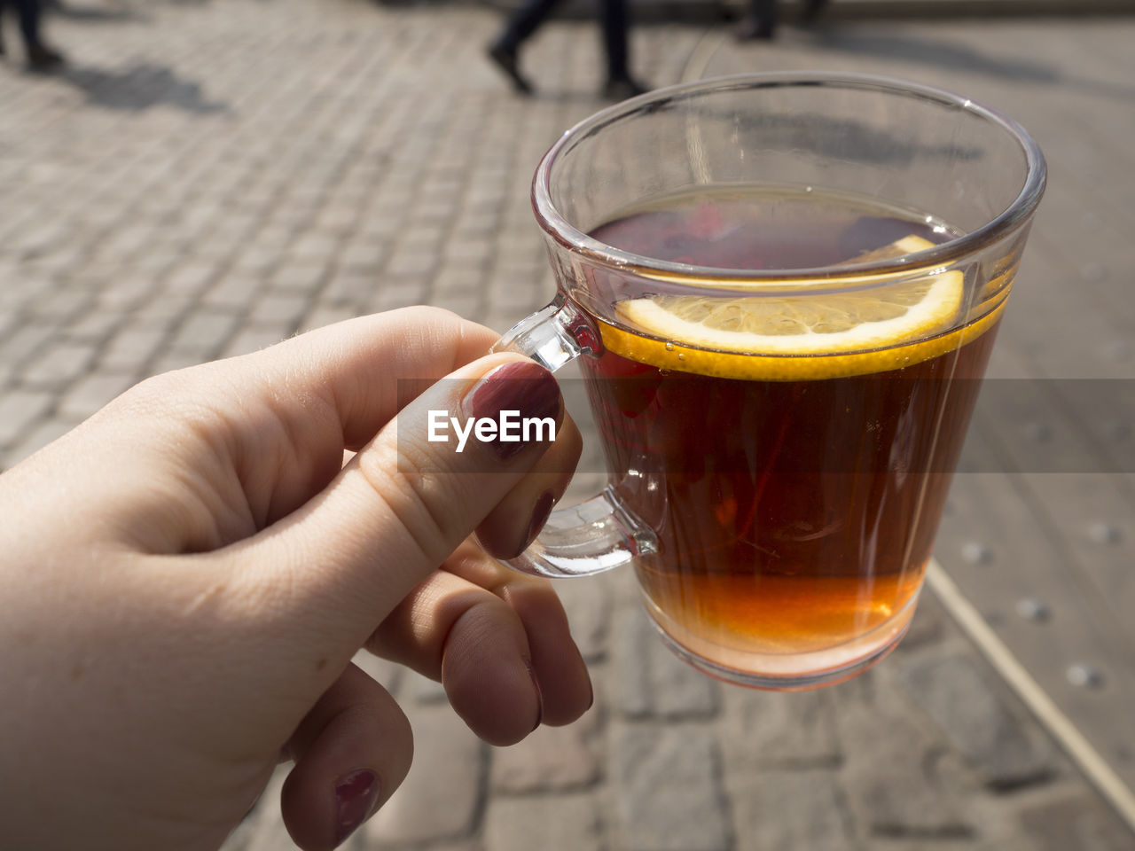 CLOSE-UP OF HAND HOLDING DRINK ON GLASS