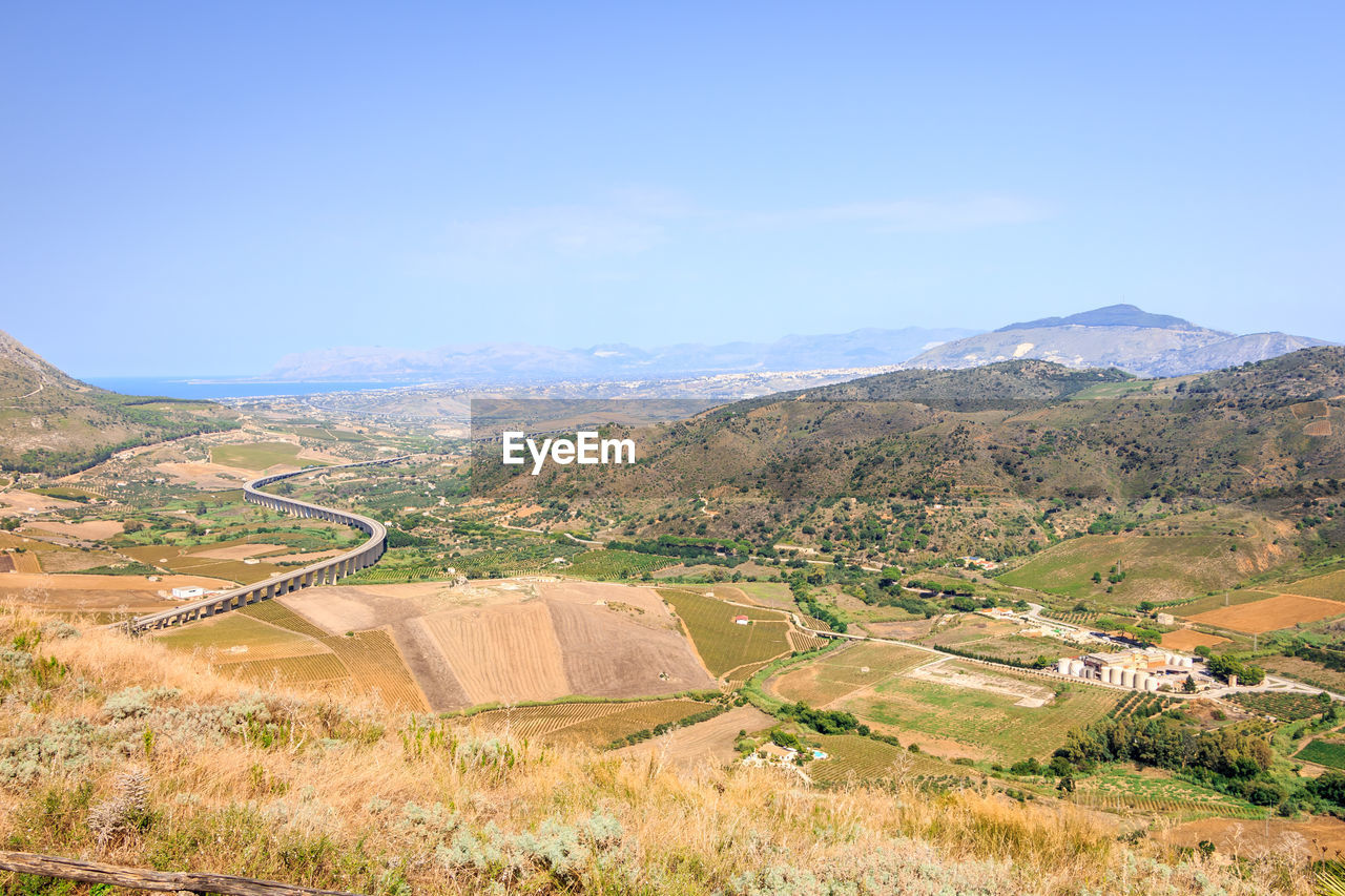 HIGH ANGLE VIEW OF FIELD AND MOUNTAINS AGAINST SKY