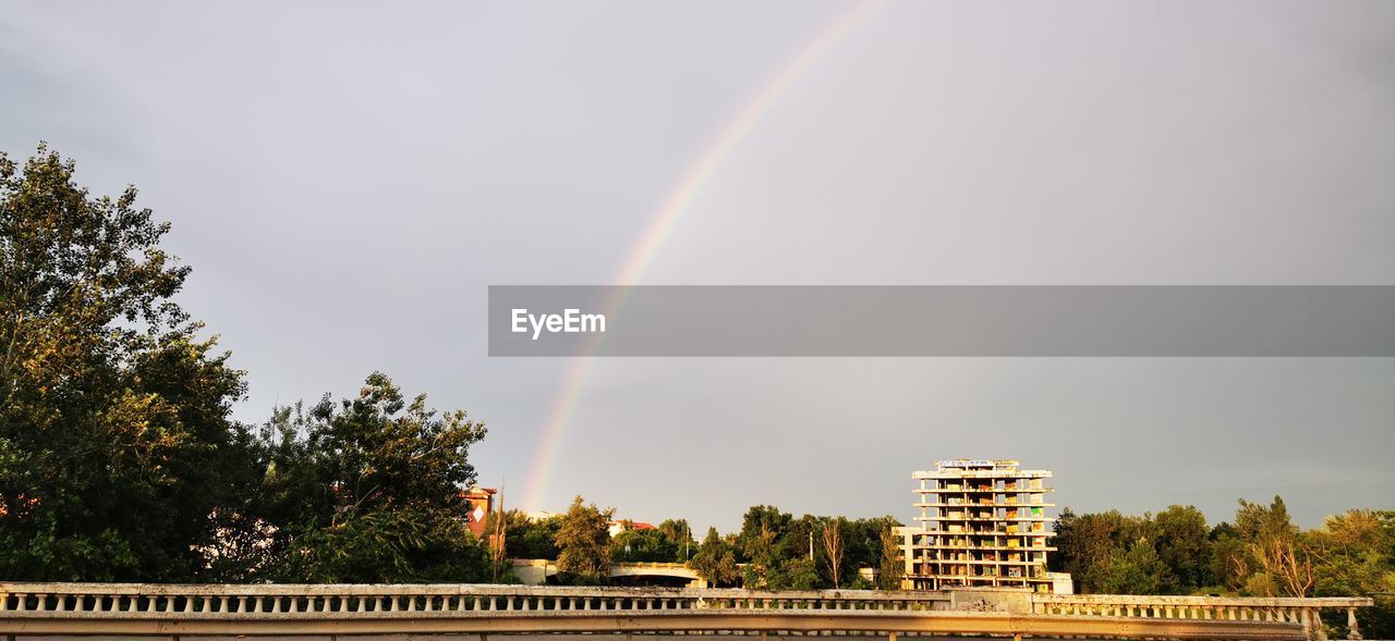 Low angle view of rainbow over building against sky