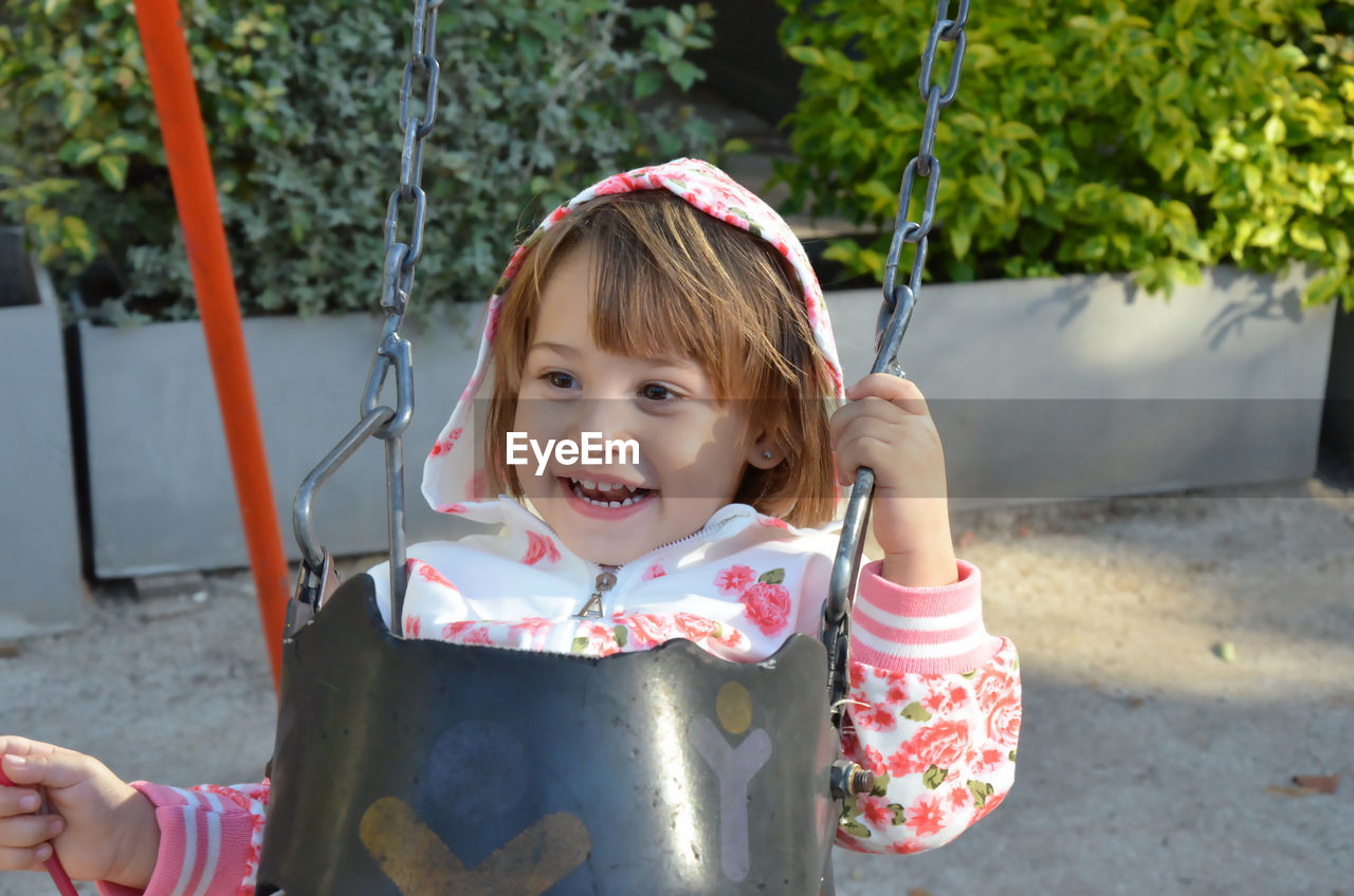 Portrait of little blonde girl on swing smiling