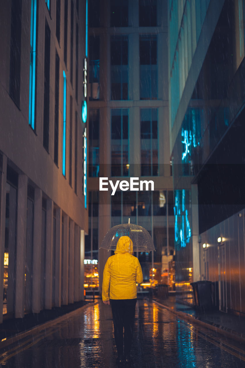 rear view of man standing by river in city at night