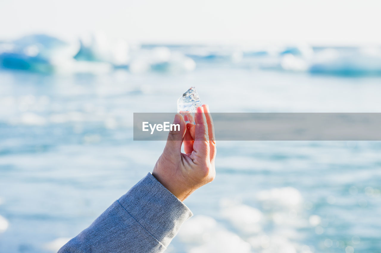 Cropped hand holding ice by glacier