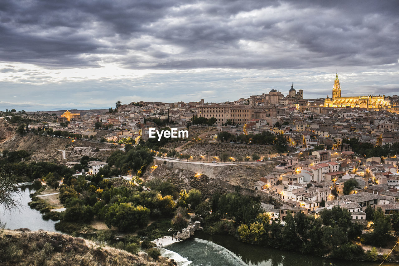 High angle view of illuminated city against cloudy sky