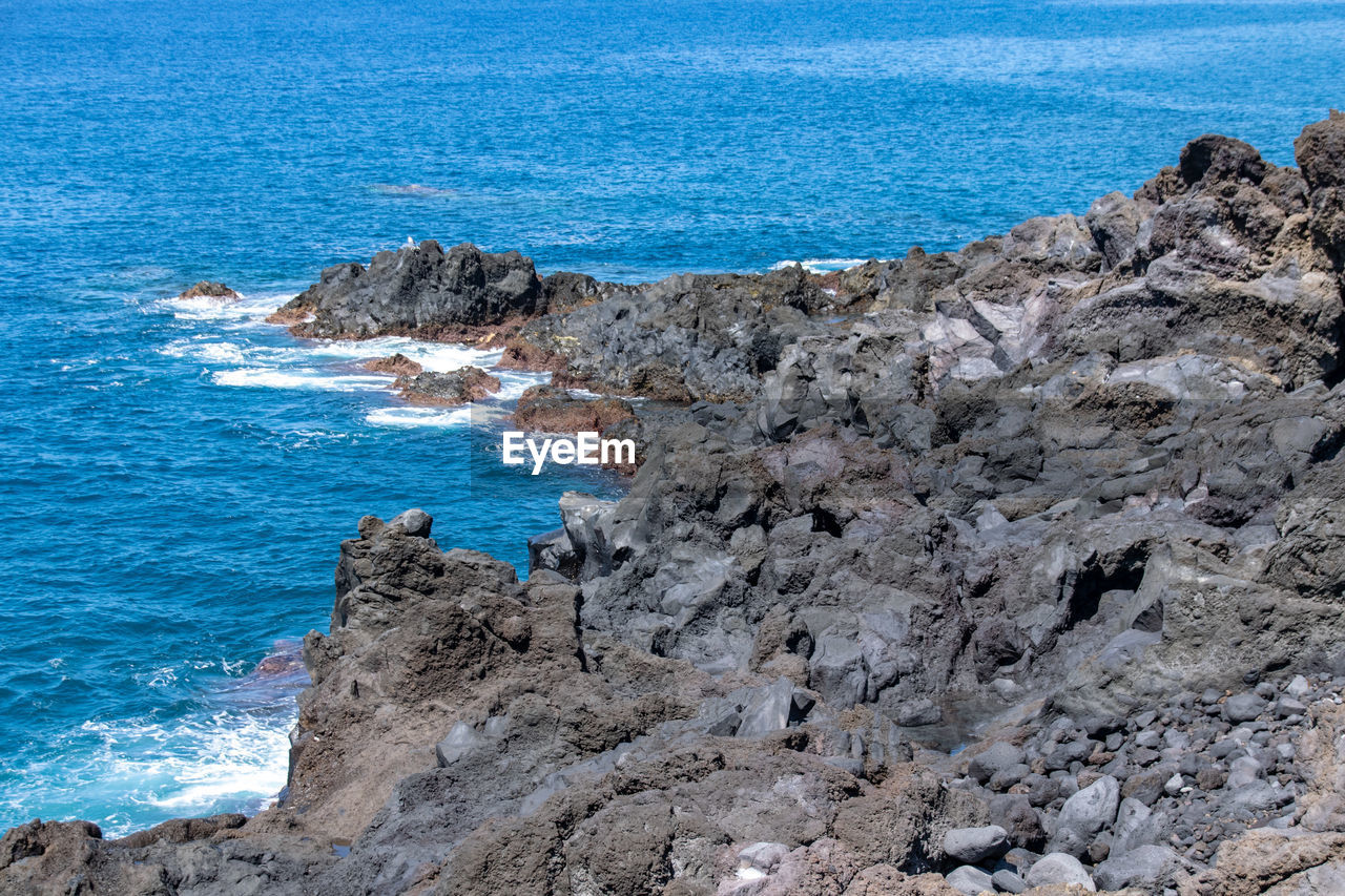 sea, water, rock, beauty in nature, land, scenics - nature, beach, cliff, rock formation, nature, ocean, shore, day, coast, tranquility, tranquil scene, terrain, no people, blue, sky, horizon, horizon over water, high angle view, idyllic, outdoors, geology, non-urban scene, promontory, cove, islet, rocky coastline, wave, body of water