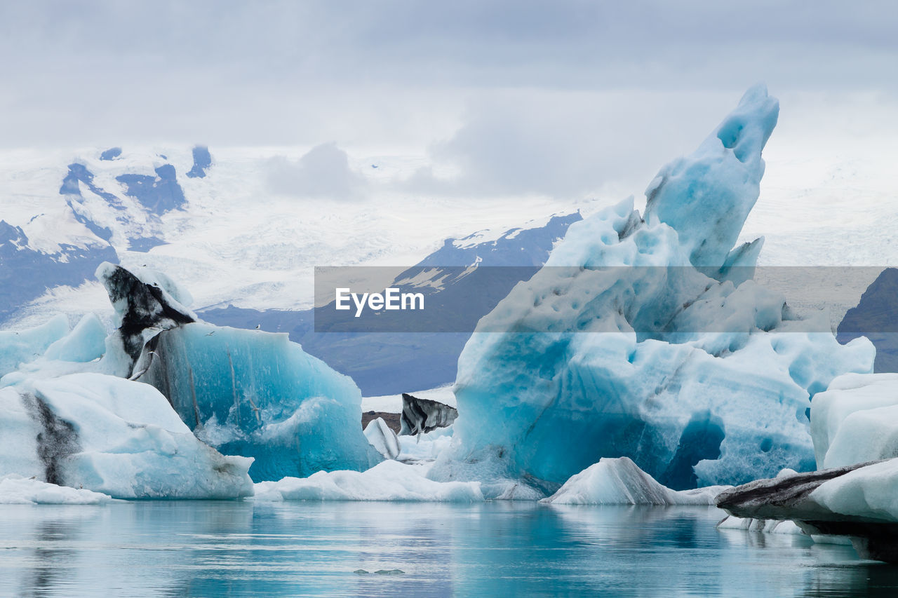 Scenic view of glacier in sea against mountains