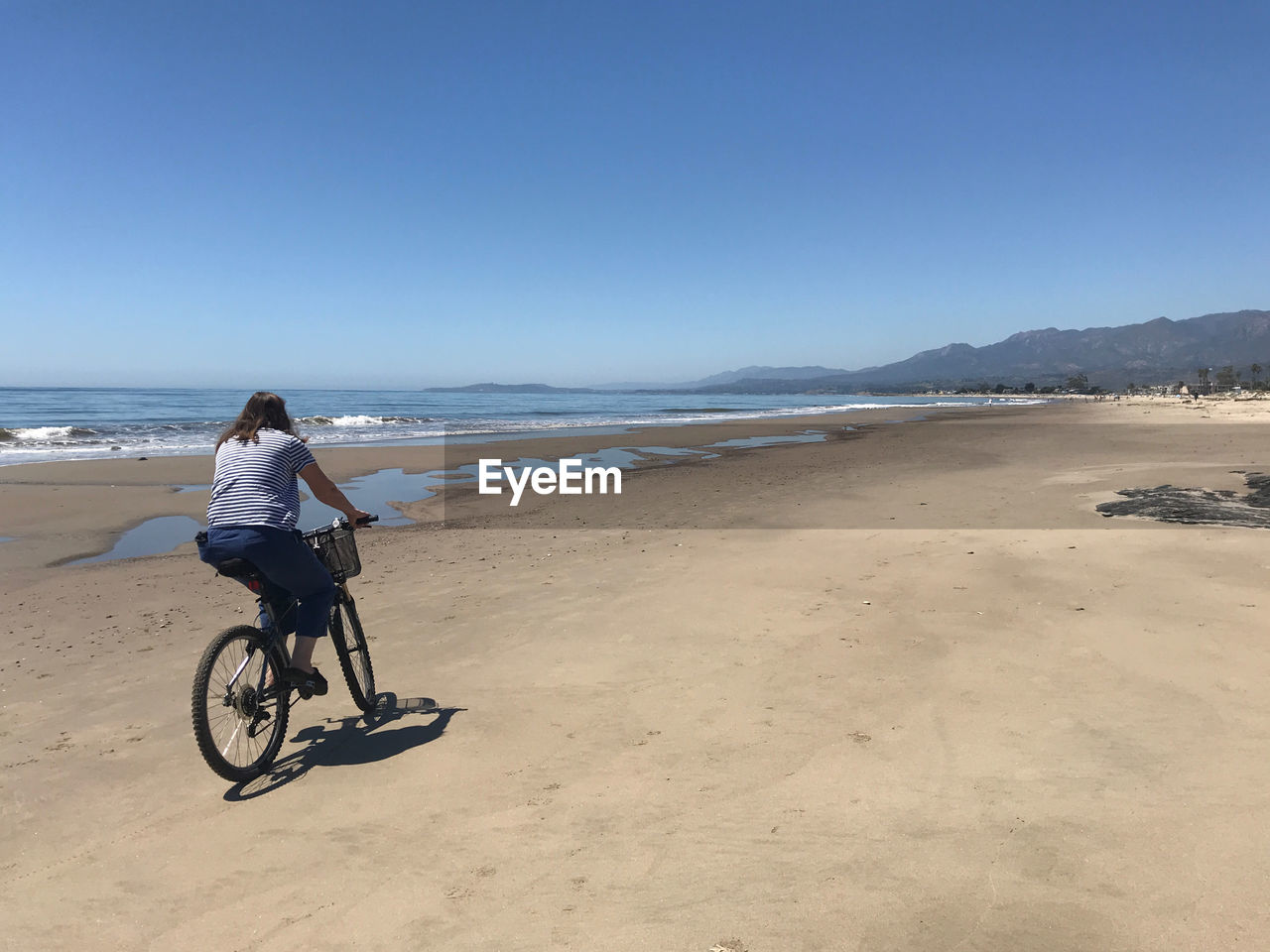Senior woman  riding bicycle on beach