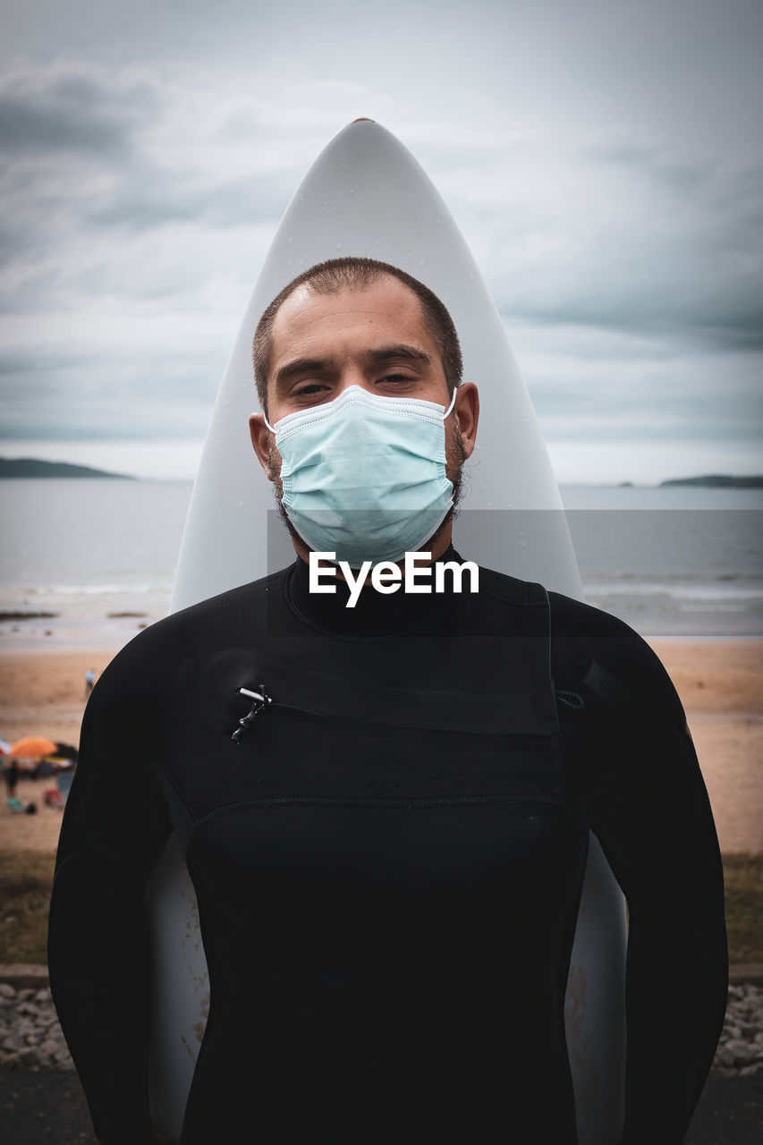 Surfboard surfer, man in mask and wetsuit on the beach