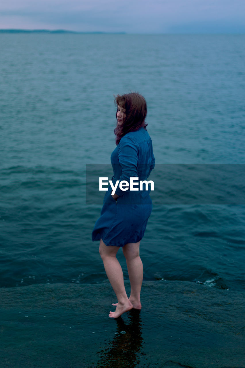 Young girl on a background of the sea in a blue dress, portrait