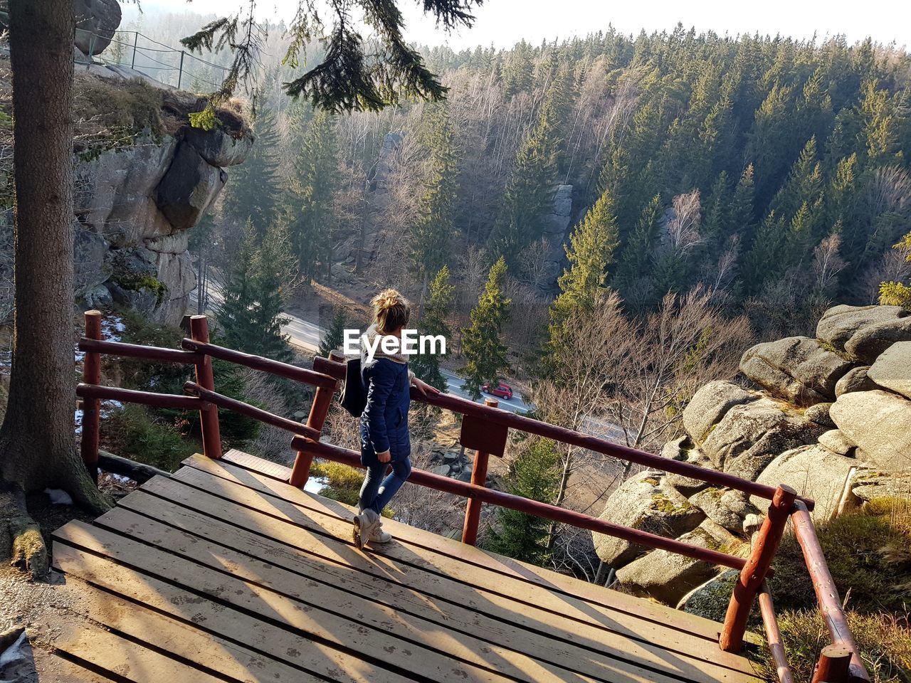 Side view of young woman standing on observation point in forest