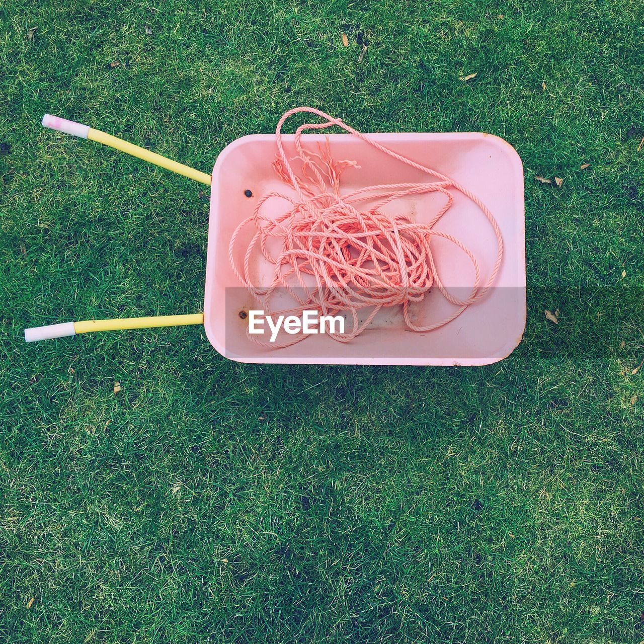 Directly above shot of ropes in wheelbarrow on grassy field