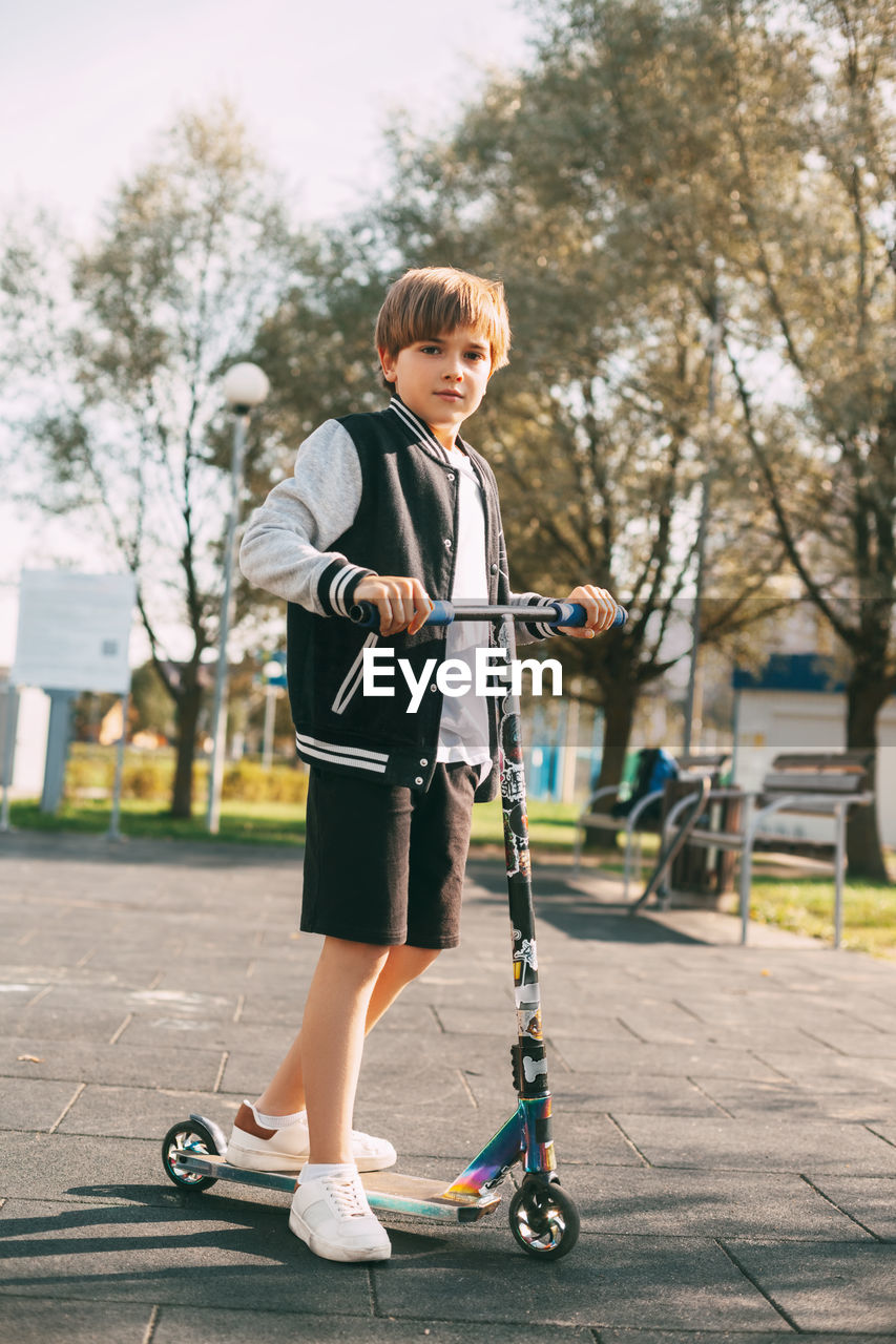 FULL LENGTH OF BOY STANDING WITH UMBRELLA ON STREET