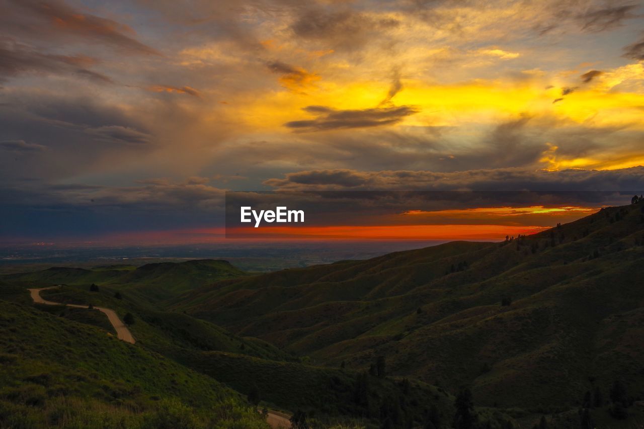 Scenic view of landscape against dramatic sky during sunset