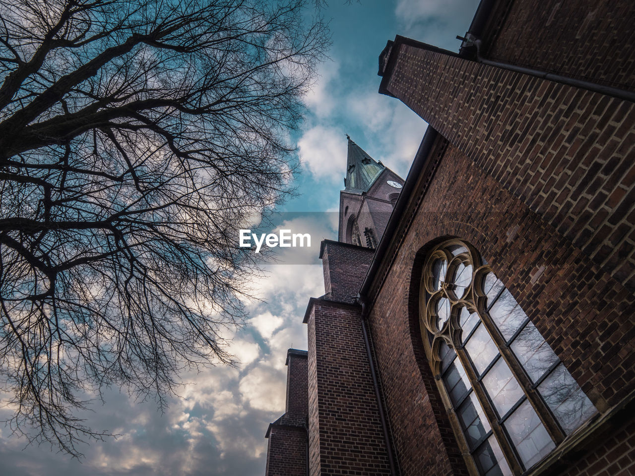 LOW ANGLE VIEW OF CLOCK TOWER AND BARE TREE AGAINST SKY