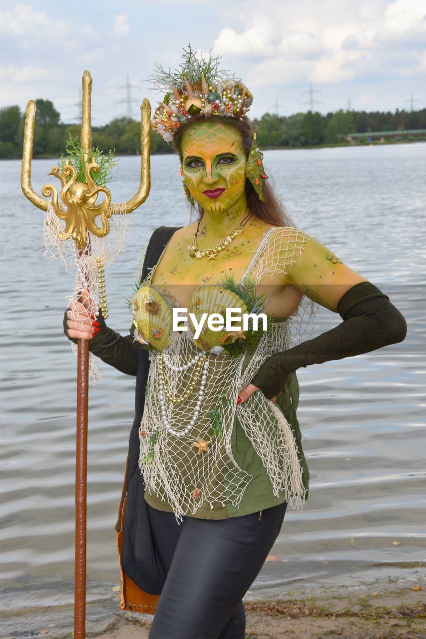 Portrait of woman standing in costume against lake