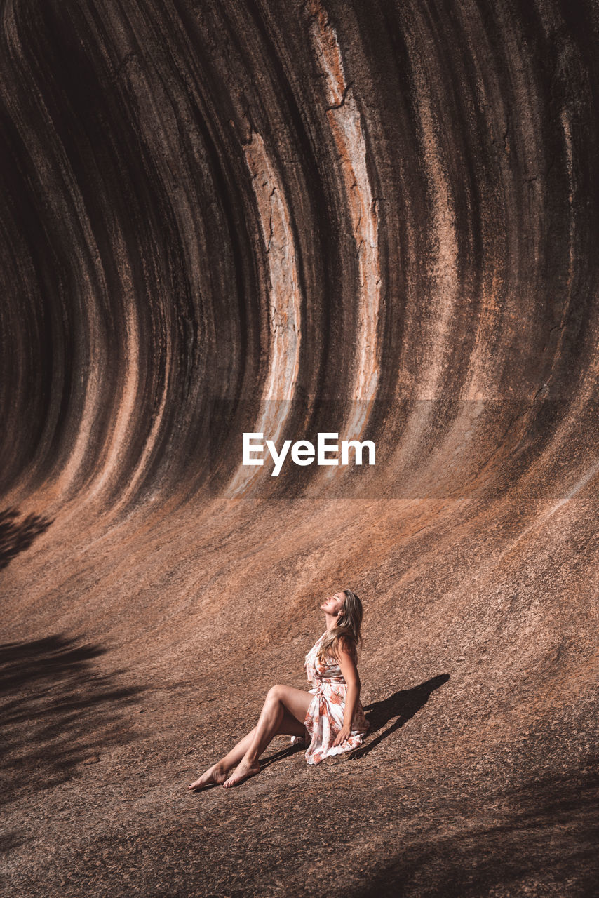 Side view of woman sitting against wall