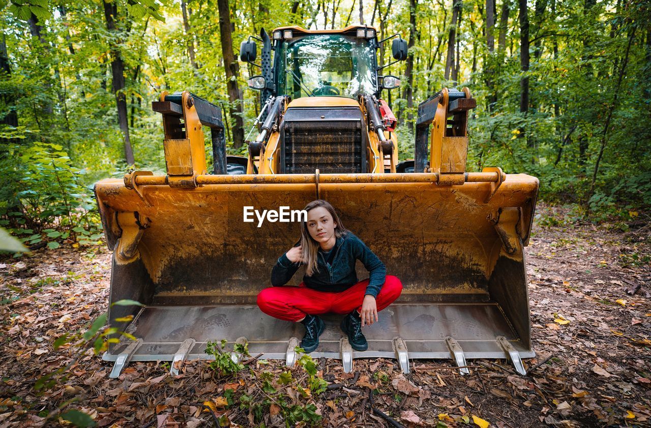 Portrait of woman sitting on excavator in forest