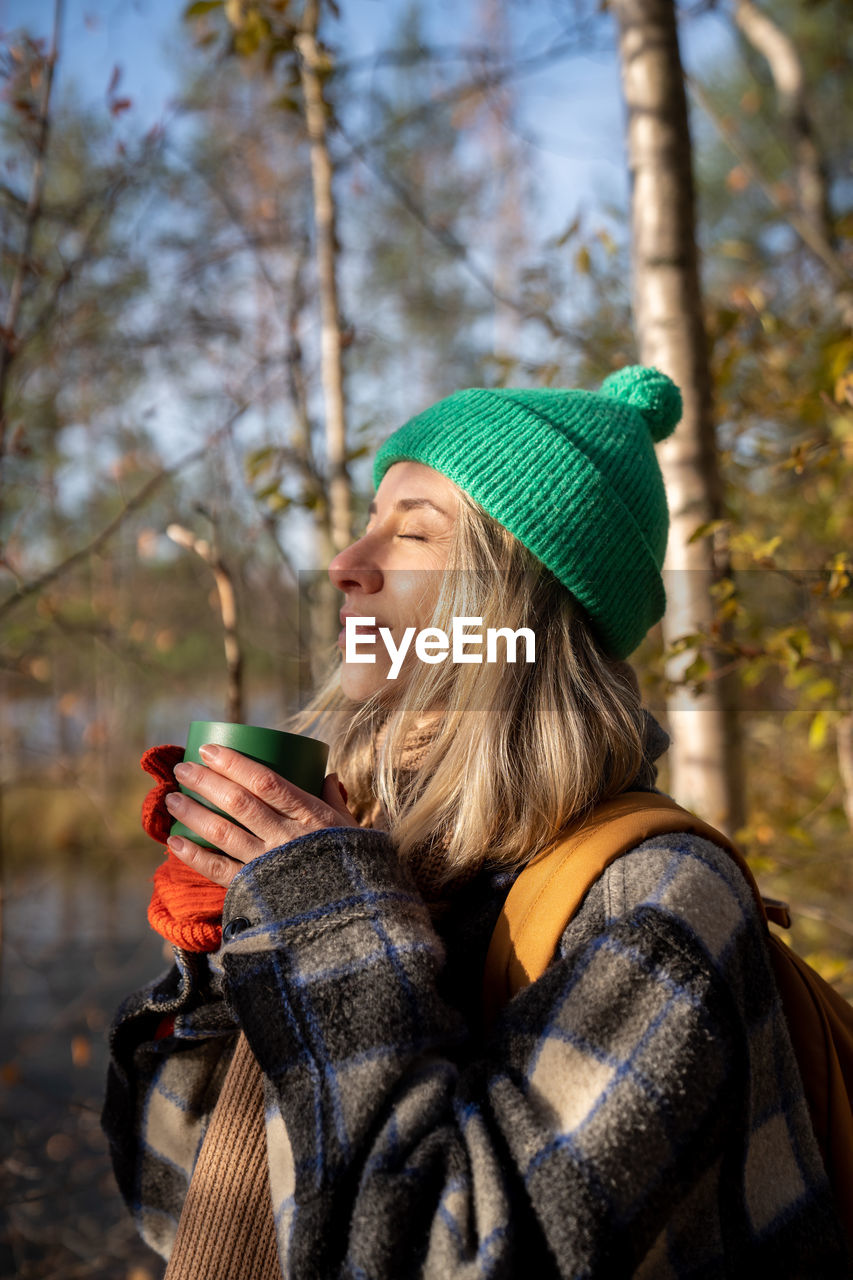 Portrait tourist woman hiker camper drinking hot tea from cup enjoying resting on nature.