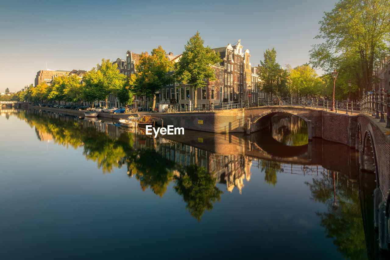 Reflection of building and trees in lake against sky