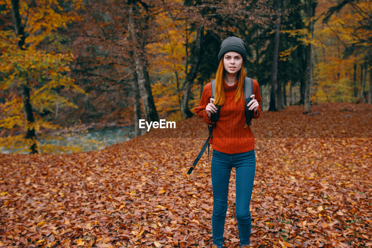 Portrait of young woman standing in forest during autumn