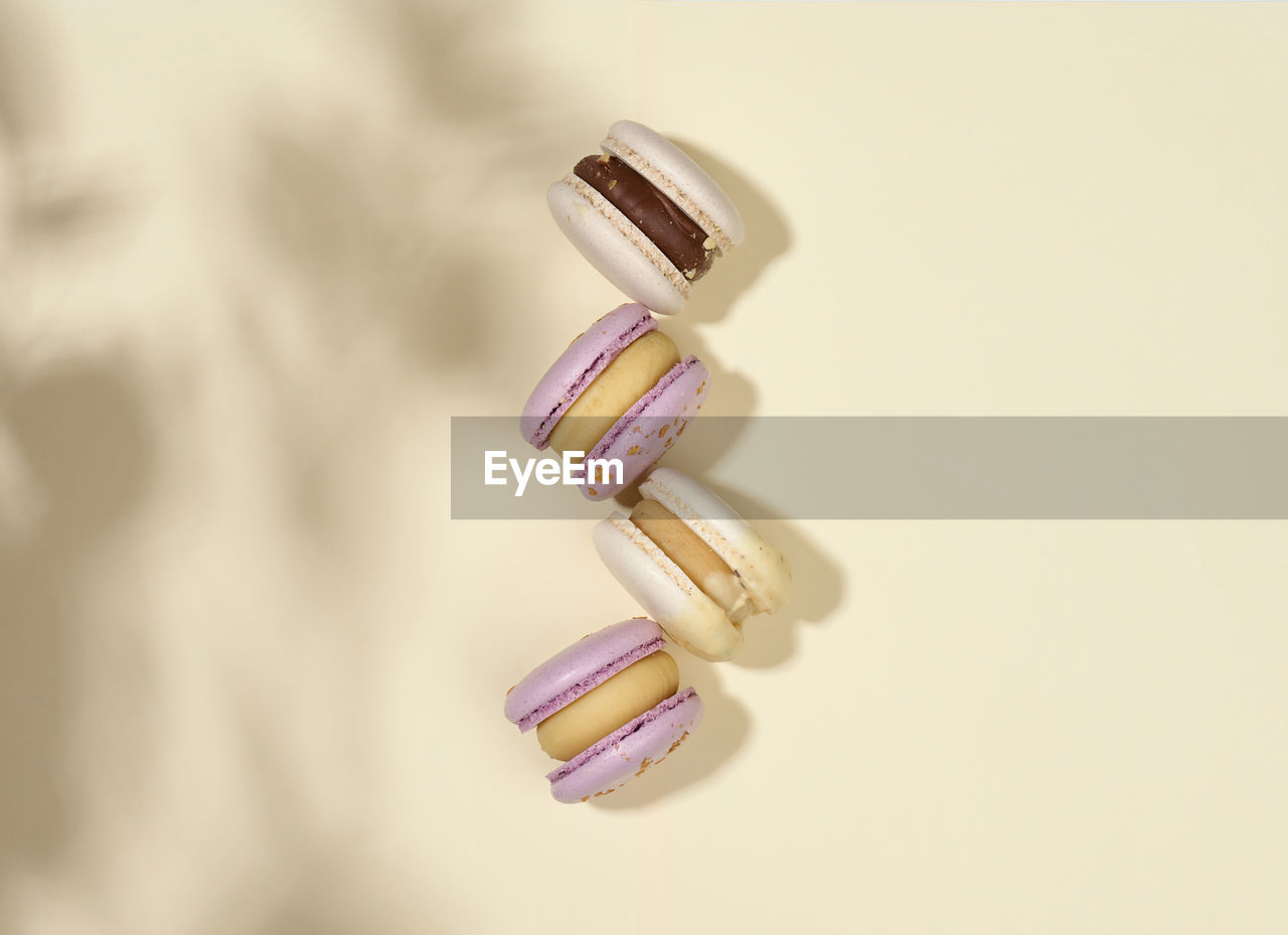 Baked macarons with different flavors on a beige background, top view