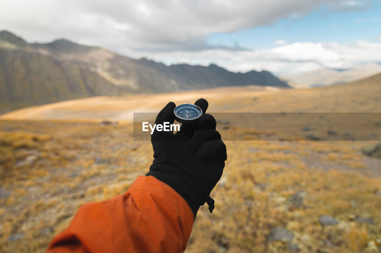 First-person view of a male traveler's hand holding a magnetic compass against the backdrop 