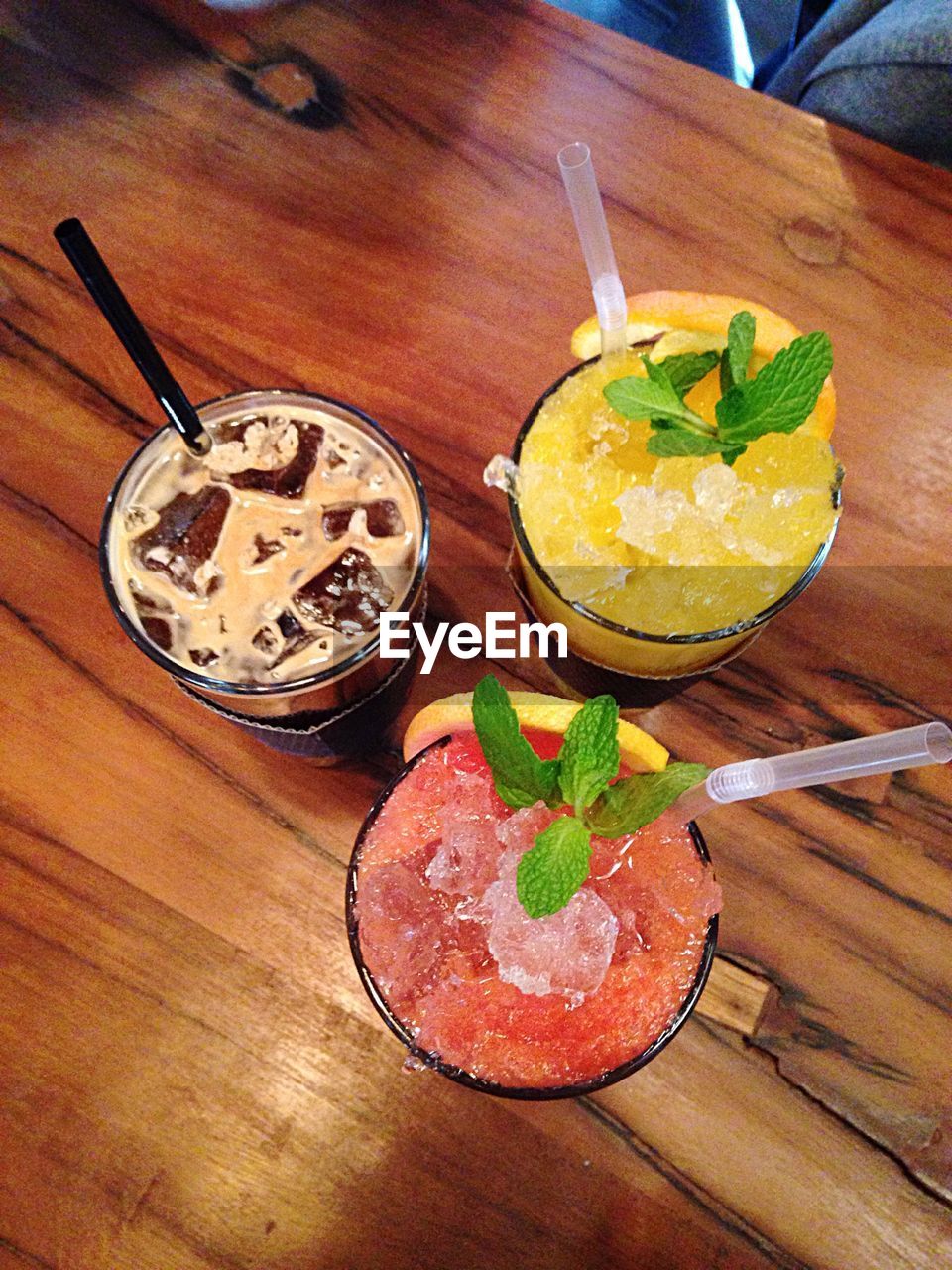 High angle view of iced coffee and juices on wooden table