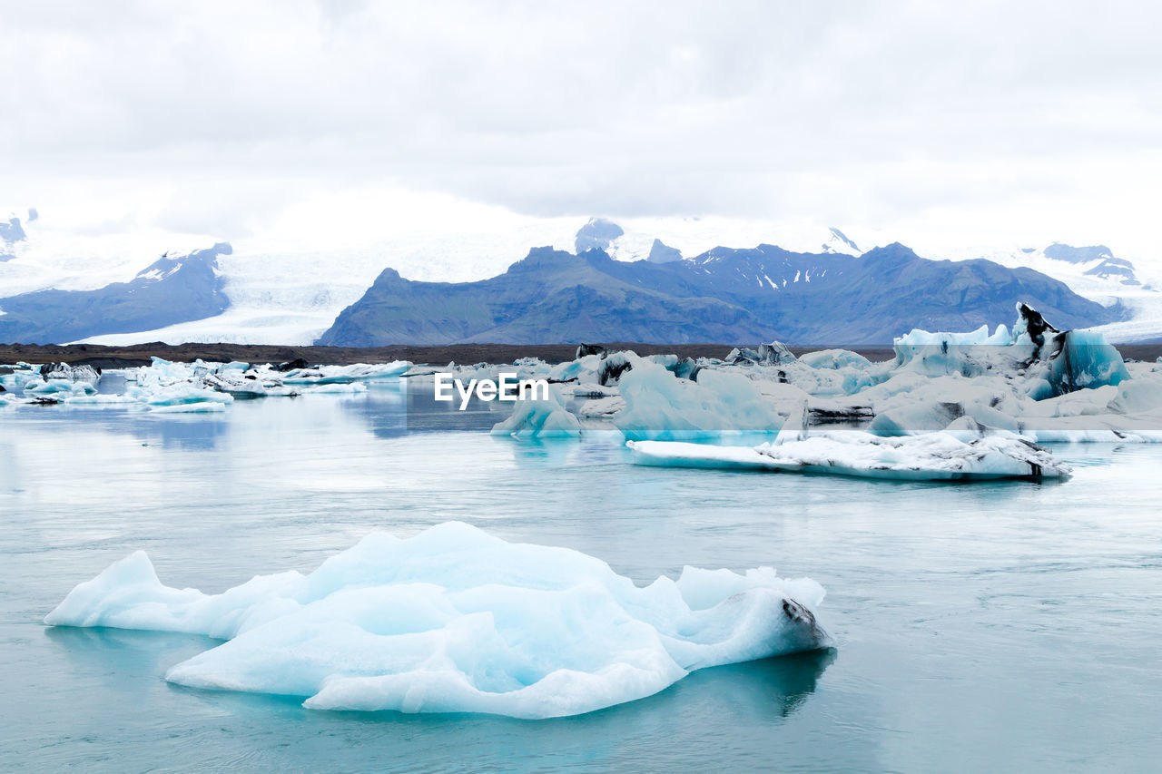 SCENIC VIEW OF FROZEN LAKE AGAINST SNOWCAPPED MOUNTAIN