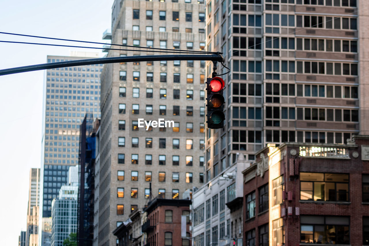 LOW ANGLE VIEW OF ROAD SIGNAL AGAINST BUILDINGS