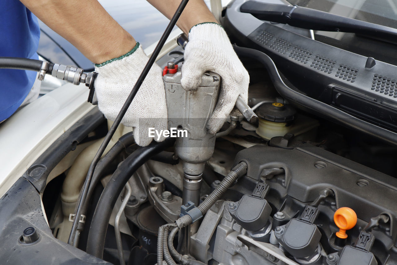 Cropped hand of mechanic repairing car in garage