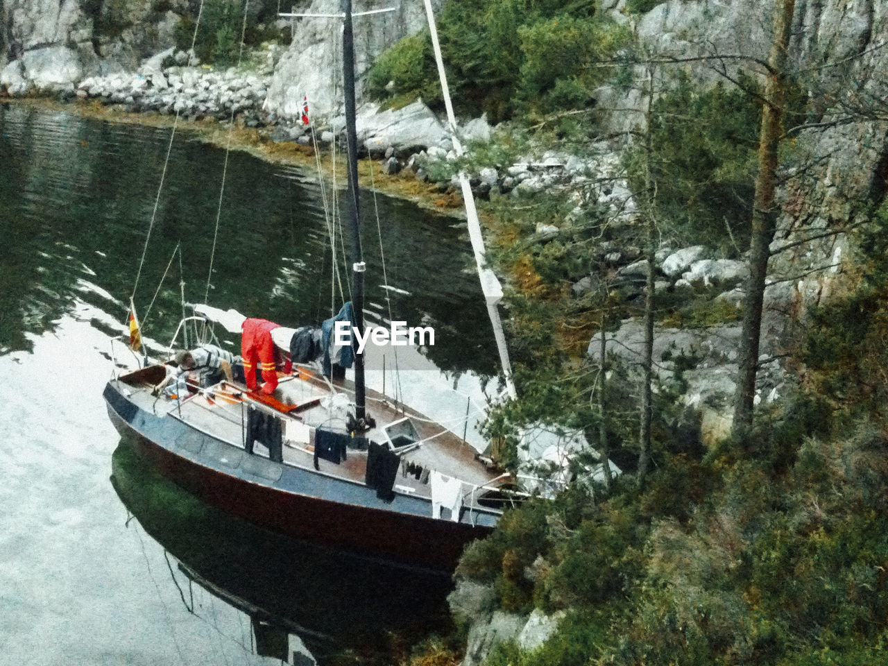 BOAT SAILING ON TREE BY MOORED BOATS