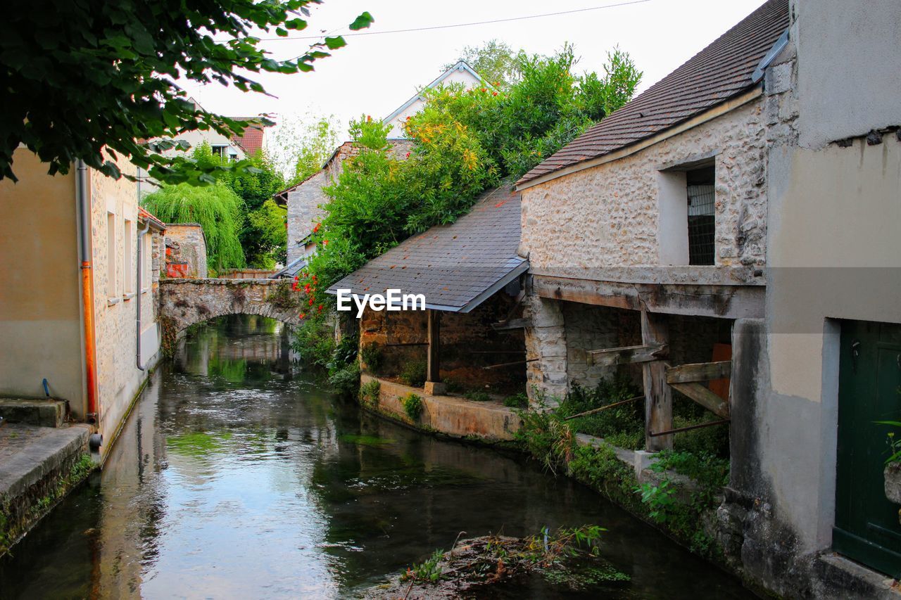 Canal amidst old buildings against sky