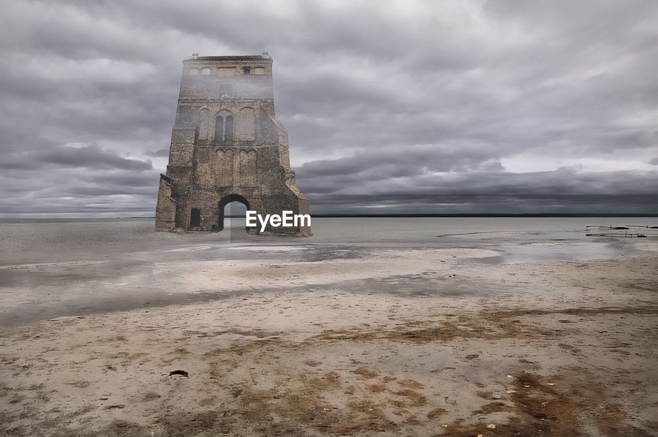 Old ruin on beach by sea against sky