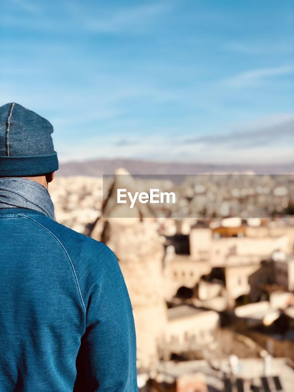 Rear view of man standing against blue sky