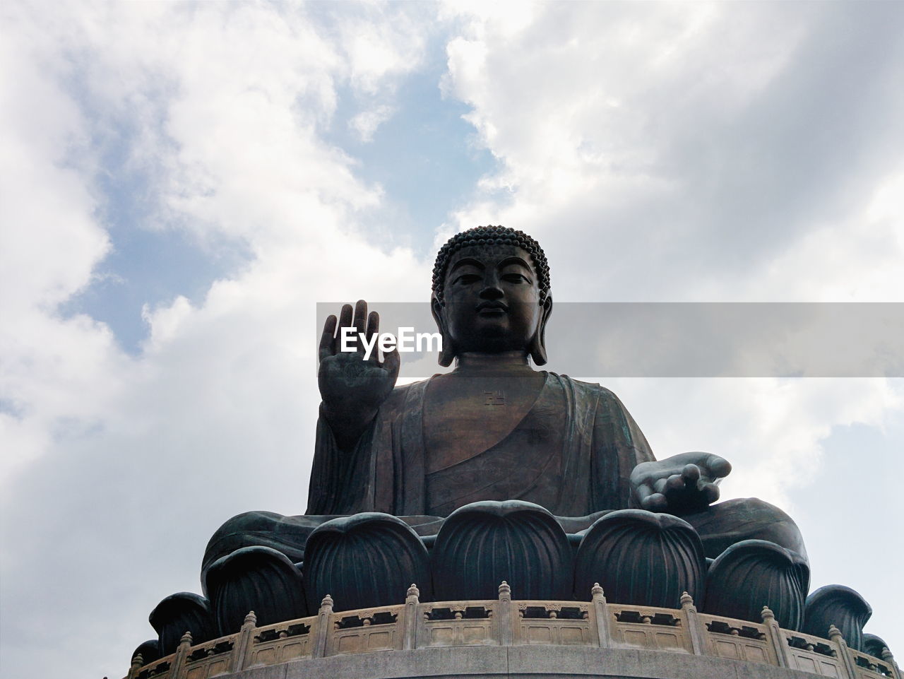 Low angle view of tian tan buddha against cloudy sky