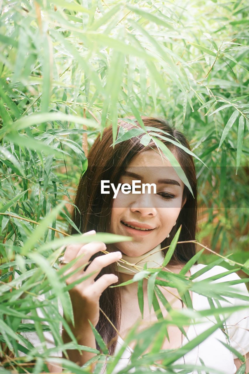 Smiling young woman by leaves 