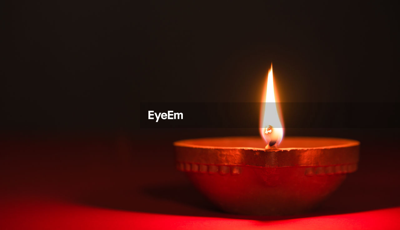 Close-up of lit candle in the dark