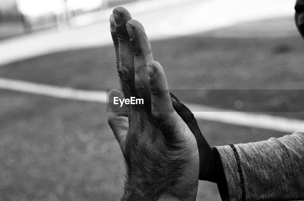 Cropped hands of father and child doing high-five outdoors