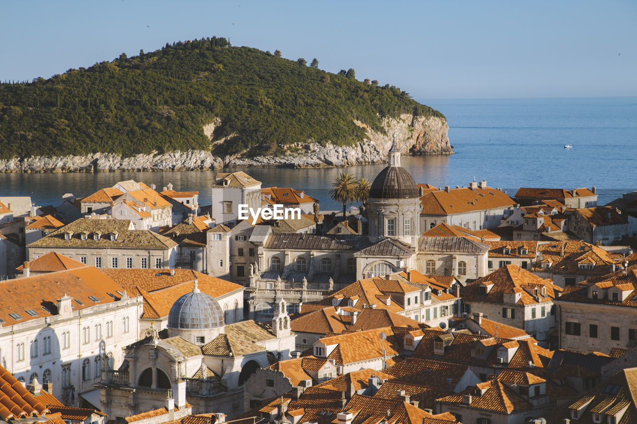 Aerial view of townscape by sea against sky