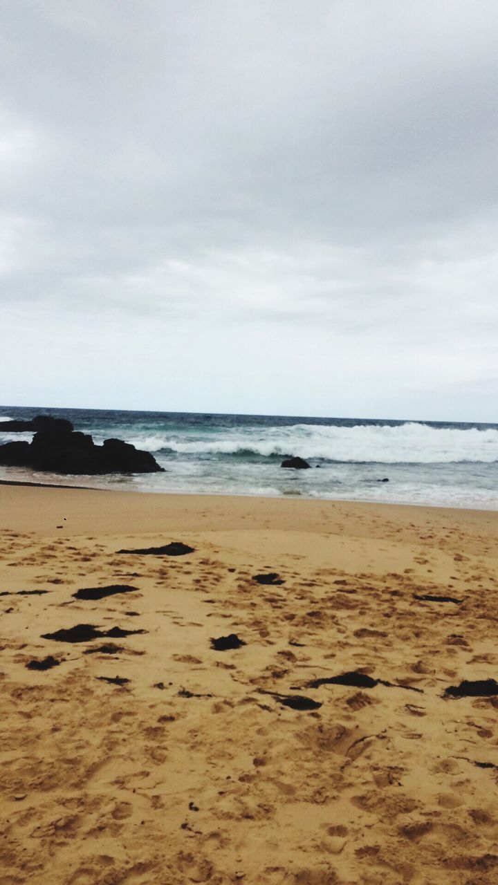 Scenic view of beach against cloudy sky