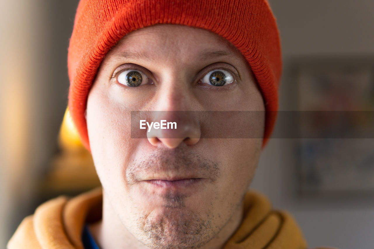 Close-up of nervous man with open green and yellow eyes and his tight lips