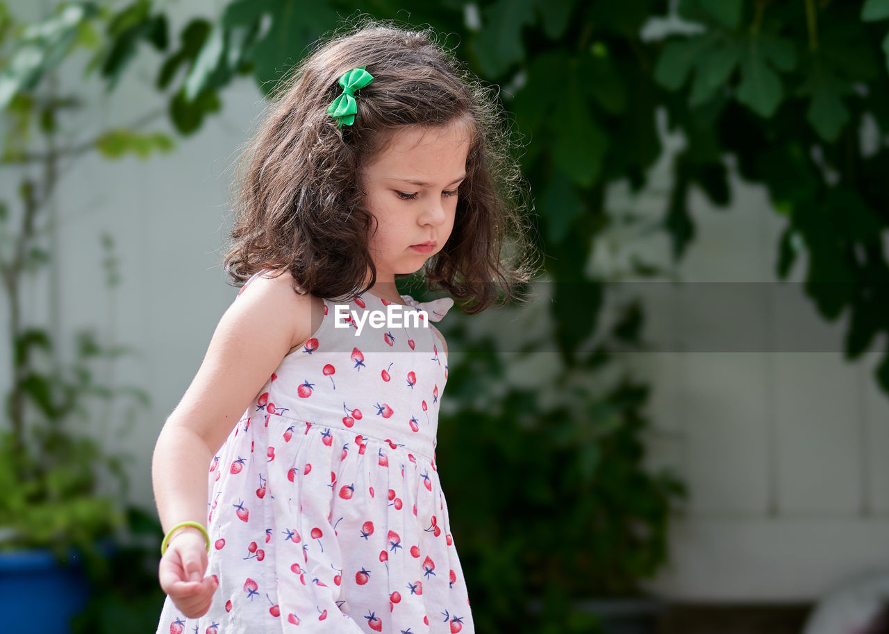 Expressive young girl in the summer dress enjoying the backyard